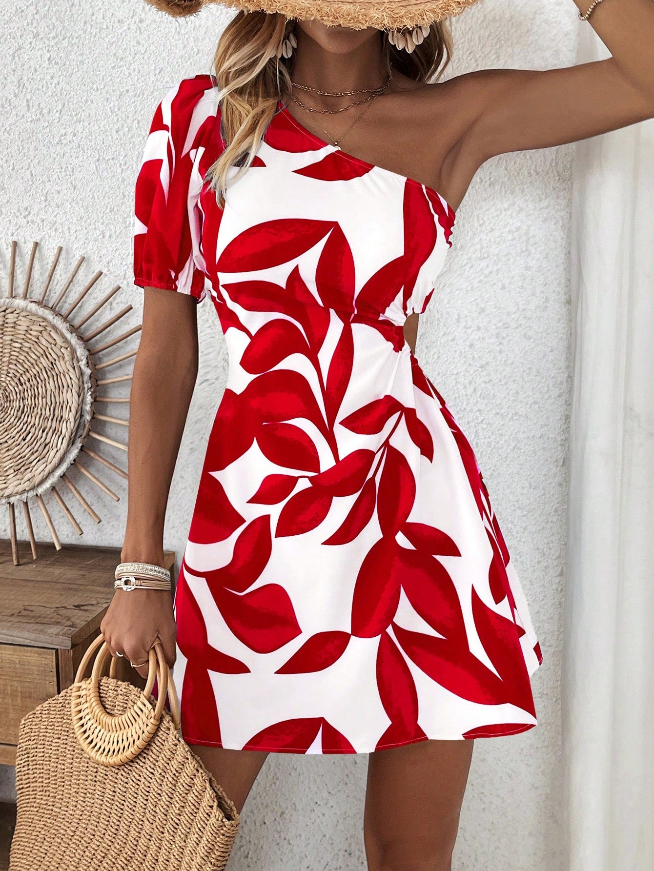 Asymmetrical short mini on white background with two toned bright red leaf print. one arm is bare and the other arm has a short sleave on it. Model is facing forward